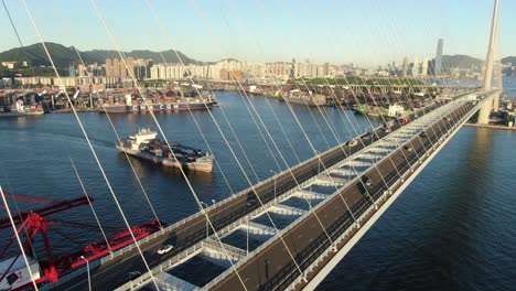 Large-Container-Ship-leaving-Hong-Kong-bay-under-Stonecutters-bridge,-Aerial-view