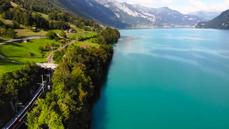 Antenne:-Elektrischer-Zug-Entlang-Eines-Blauen-Sees-In-Den-Alpen