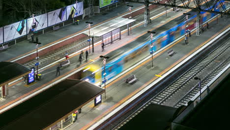 Time-lapse-at-night-looking-down-on-trains-and-passengers-at-the-South-Yarra-railway-station-in-Melbourne,-Australia