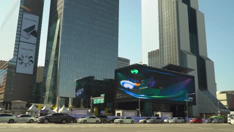 Tráfico-De-Automóviles-Cerca-Del-Centro-De-Comercio-Mundial-Seúl---Sttown-Coex-Artium-Con-La-Pantalla-De-Cartelera-Digital-Al-Aire-Libre-Curvada-Más-Grande,-Torre-De-Comercio-Y-Rascacielos-Parnas-Al-Atardecer,-Corea-Del-Sur