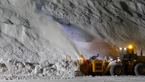 Schwerer-Bulldozer-In-Zeitlupe,-Der-Schnee-Von-Der-Straße-Zu-Einem-Riesigen-Schneehaufen-Bläst,-Schneefräse,-Die-Nachts-Arbeitet