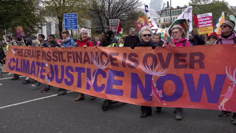 Demonstranten-Tragen-Ein-Orangefarbenes-Banner-Mit-Der-Aufschrift-„Die-Ära-Der-Fossilen-Finanzierung-Ist-Vorbei,-Klimagerechtigkeit-Jetzt“-Bei-Protesten-Zur-Hervorhebung-Der-Klimakrise-Während-Des-Cop-26-Gipfels