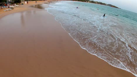 Aerial-flying-over-beach-in-Mirissa-at-sunset,-tourists-having-fun,-Sri-Lanka