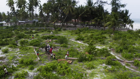 Drone-videomaker-surrounded-by-black-kids-in-tropical-coastal-town