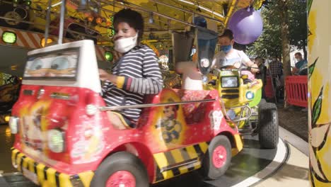 Niños-Felices-Y-Emocionados-Montando-En-Coloridos-Vehículos-De-Juguete-En-El-Parque-De-Atracciones