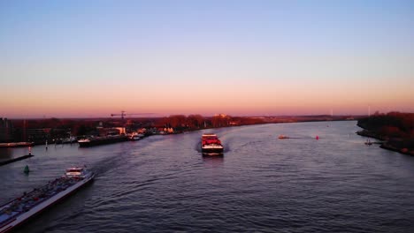 Aerial-View-Of-Victoria-Cargo-Ship-Approaching-Along-Oude-Maas-Against-Orange-Warm-Skies