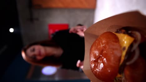 Vertical-Rack-Focus-Shot-Of-Tasty-Juicy-Hamburger-served-To-Beautiful-smiley-Lady-Waiting-Her-Delicious-Meal