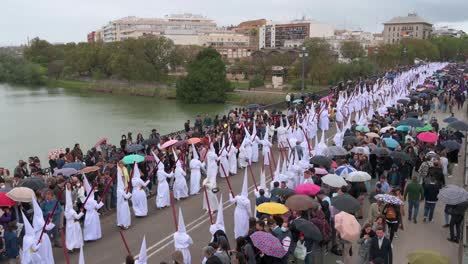 Penitentes-Marchan-Durante-Una-Procesión-Cruzando-El-Puente-De-Triana-En-Celebración-De-La-Semana-Santa-En-Sevilla,-España