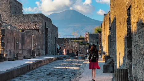 Toma-En-Cámara-Lenta-De-Una-Mujer-Caminando-Entre-Las-Antiguas-Murallas-De-Pompeya-En-Italia---Volcán-Gigante-Rodeado-De-Nubes-En-El-Fondo