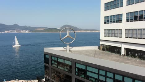 Mercedes-Benz-sign-spinning-on-top-of-Hong-Kong-Mercedes-Benz-main-showroom,-Aerial-view