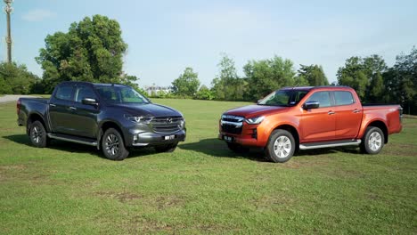 Malaysia,-March-13,-2022:-two-4x4-Isuzu-D-Max-pick-ups-in-dark-orange-color-and-black-on-a-grassy-field