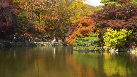 Many-People-in-masks-walking-on-stone-pagoda-by-Chundangji-pond,-Changgyeonggung-Palace,-Seoul-South-Korea