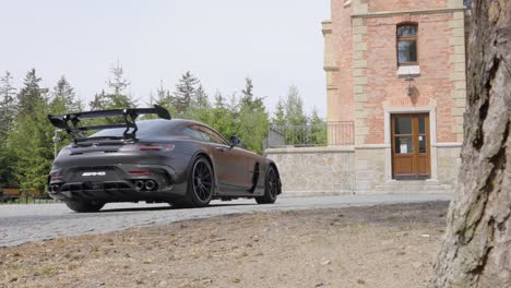 Coche-Deportivo-Negro-Conduciendo-Hacia-Una-Mansión---Toma-Panorámica