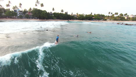 Tiro-De-Seguimiento-De-Surfistas-Montando-Olas-Rápidas-En-Un-Hermoso-Día-De-Verano,-Sri-Lanka