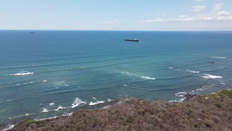 Aerial-view-of-a-cargo-ship-near-the-seashore,-in-calm-blue-waters