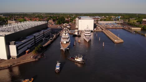 Luftaufnahme-Von-Schleppern,-Die-Der-Luxusyacht-Helfen,-Am-Yachthafen-Der-Oceanco-Werft-Anzudocken