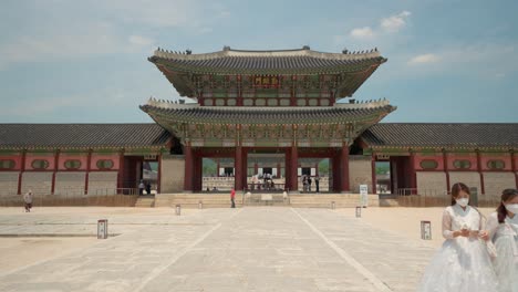 Koreanische-Mädchen-In-Schützenden-Gesichtsmasken-Und-Hanbok-kleidern-Reisen-Während-Der-Covid-19-pandemie-Im-Gyeongbokgung-palast