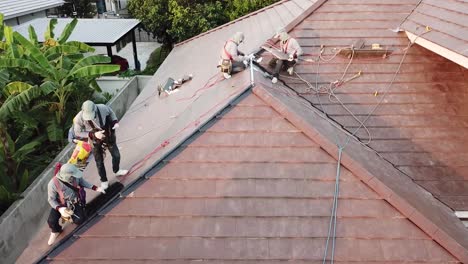 Asian-Technician-Work-on-Roof-Installation,-Aerial-Shot