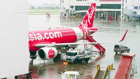 Airasia-Airlines-Docken-An-Der-Halle-An,-Während-Sie-Sich-An-Einem-Regnerischen-Tag-Mit-Bodenpersonal-Auf-Dem-Internationalen-Flughafen-Don-Mueang-dmk-Auf-Den-Abflug-Vorbereiten