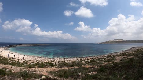 MALTA-COASTLINE-TIMELAPSE-SWIVEL-ROTATING-FANTASTIC-VIEW-BLUE-SEA-AND-SEAFRONT-ROCK-BEACH,-FAST-MOVING-CLOUDS,-SHELL-SHAPE-COAST