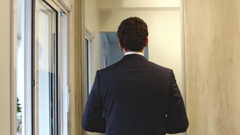 Dolly-left-revealing-groom-getting-ready-in-front-of-mirror-for-wedding-ceremony