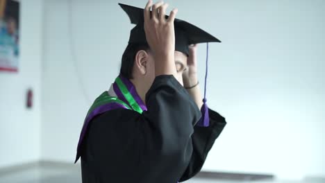 Hombre-Apuesto-De-Unos-20-Años-Poniéndose-Una-Toga-Y-Birrete-De-Graduación