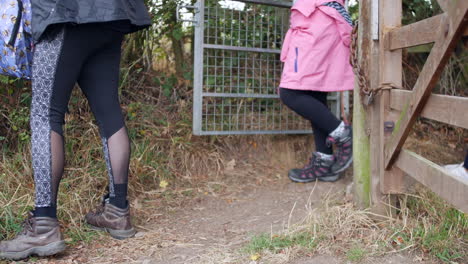 A-family-with-a-dog-walking-through-the-countryside-opening-a-gate-on-a-path