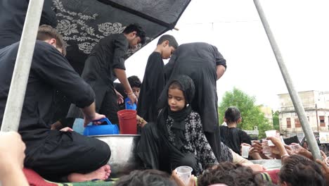 Un-Chico-Y-Una-Chica-Joven-Están-Sirviendo-Sharbat-A-Los-Dolientes-En-Los-Juloos,-O-Desfile,-De-Muharram,-También-Conocido-Como-Muharram-Ul-Haram