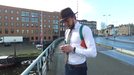 Un-Hombre-Elegante-En-Estilo-Dandy-Con-Camisa-Blanca-Y-Barba-Hace-Una-Llamada-Telefónica-En-El-Puente-Kadijksplein-En-Amsterdam