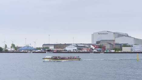 Sightseeing-canal-tours-boat-with-tourists-sailing-in-front-of-Refshaleøen-in-Copenhagen,-Denmark