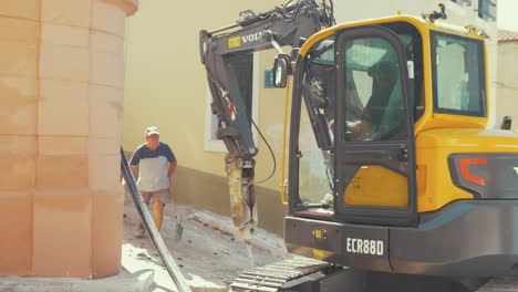 Digger-with-rocker-breaker-attachment-breaking-concrete-for-water-pipe-maintenance-slow-motion