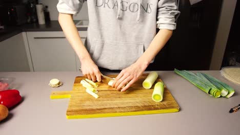 Mujer-Cortando-Puerros-Sobre-Una-Mesa-De-Madera