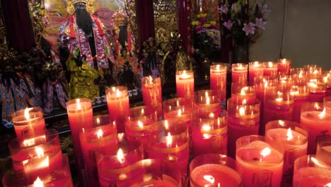 Toma-En-Cámara-Lenta-De-Velas-Rojas-Frente-A-La-Figura-Religiosa-En-El-Templo-Longshan-En-Taipei,-Taiwán