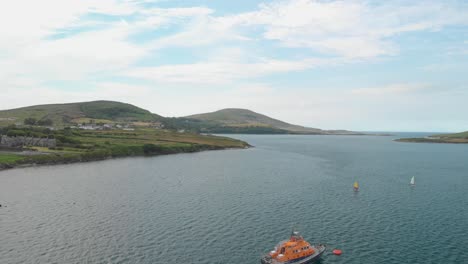 Sobrevuelo-Aéreo-Del-Bote-Salvavidas-Anclado-Con-2-Pequeños-Botes-De-Vela-Acercándose,ubicación-Península-De-Iveragh,-Portmagee-A-La-Izquierda-Y-La-Isla-De-Valentia-A-La-Derecha,-Co-Kerry