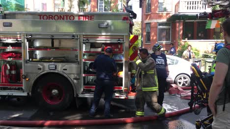 Tiro-De-Bomberos-Y-Policías-De-Toronto-Trabajando-Alrededor-De-Una-Brigada-De-Bomberos-En-Un-Lugar-De-Accidente-Después-Del-Accidente-Con-Otras-Personas-Observándolos,-Durante-Una-Tarde