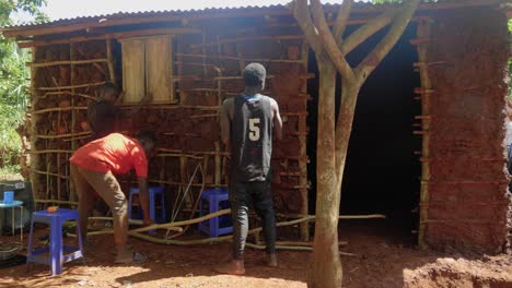 Wide-shot-of-Africans-packing-mud-onto-the-walls-of-a-traditional-style-mud-house-in-a-rural-village-in-Africa