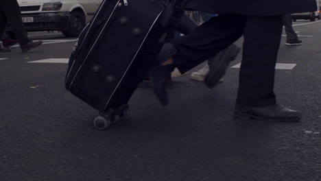 Clip-from-a-crosswalk-in-Madrid,-Spain,-with-pedestrians-walking-in-every-direction-and-a-businessman-moving-his-luggage