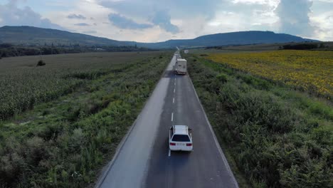 Road-and-car-traffic-surrounded-by-agricultural-land---aerial-tracking-shot