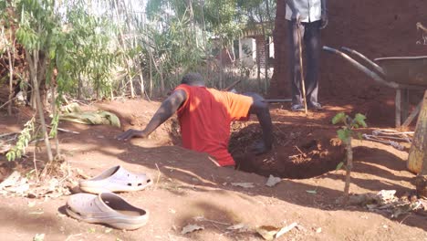 Afrikanischer-Mann-In-Einem-Ländlichen-Dorf,-Der-In-Ein-Loch-Kriecht,-Das-In-Eine-Grubenlatrine-Gegraben-Wird