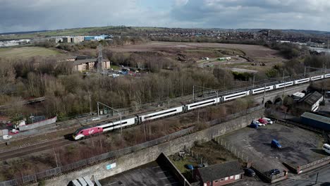 Aerial-footage-of-trains-approaching-Stoke-on-Trent-train-station-in-the-midlands-by-the-canal,-waterside-and-A50-motorway