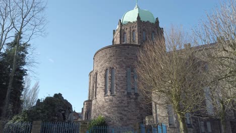 Low-angle-panning-view-across-Lowe-house-church-tower---dome-in-rural-British-town