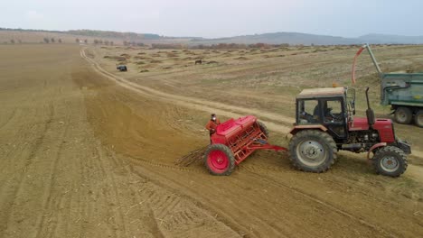 Tractor,-agricultural-machinery-and-workers-sow-a-field---aerial-tracking-shot