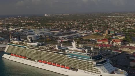 Luftaufnahme-Des-Kreuzfahrtschiffes-Im-Dock-Mit-Der-Insel-Im-Hintergrund-Und-Neigen-Der-Kamera-In-Den-Himmel