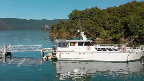 Cámara-Lenta---Crucero-Y-Bote-Pequeño-Atracados-En-La-Bahía-En-Los-Sonidos-De-Marlborough,-Nueva-Zelanda---Tiro-Aéreo-Bajo-Lateral