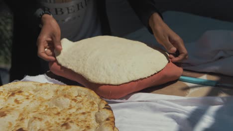 Refugee-Afghan-woman-spreads-out-dough-on-cushion-before-baking-in-traditional-Tandoor-oven-in-Moria-Refugee-Camp