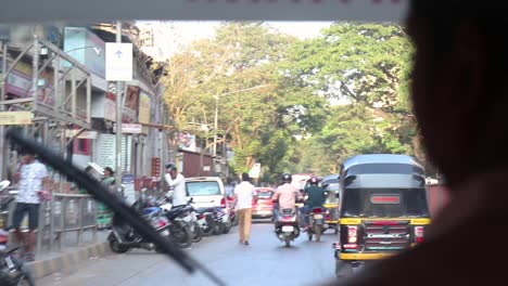 Tiro-Al-Hombro-Del-Conductor-Del-Rikshaw-Automático-Conduciendo-Por-Una-Concurrida-Carretera-India