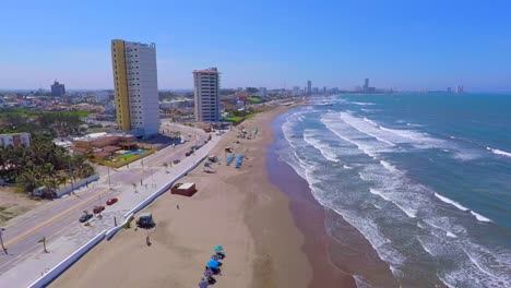 Bird´s-eye-view-of-the-coastline-Boca-del-Rio-beach,-image-from-the-heights-of-how-the-beach-looks,-with-serene-waves-and-white-sand,-the-umbrellas-accompany-the-coming-and-going-of-the-sea