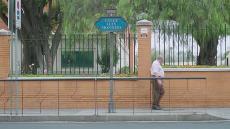 Hombre-Mayor,-Motocicleta-Y-Coche-Pasan-El-Letrero-De-La-Calle-Luis-Montoto-En-Sevilla,-Cámara-Lenta