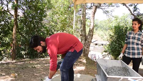 Boy-collecting-gravel-from-the-ground-using-a-shovel