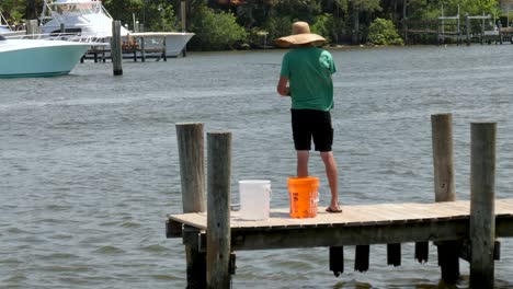 Mann-Mit-Hut-Und-Stange-In-Der-Hand-Angeln-Am-Dock---Pier-Windige-Bedingungen-Und-Den-Fisch-Zurückwerfen,-Fangen-Und-Freilassen